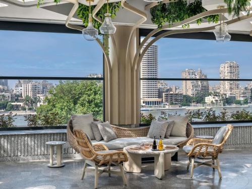 a living room with a couch and chairs and a large window at Sofitel Cairo Downtown Nile in Cairo