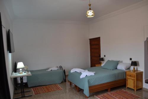 a bedroom with two beds and a table and a lamp at La Belle Vue Guest House in Aït Ben Haddou