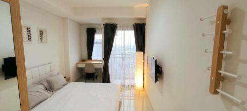 ein Schlafzimmer mit einem weißen Bett und einem Fenster in der Unterkunft Springwood Bright Escape Studio in Warungmangga