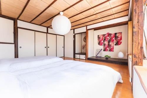 a bedroom with a white bed and a wooden ceiling at SkySTAGE十人町 in Nagasaki