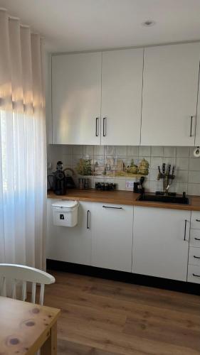 a kitchen with white cabinets and a wooden table at Refúgio da Quinta Nere Maitia in Santarém