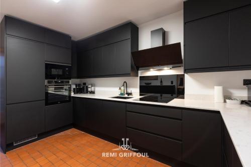 a kitchen with black cabinets and white counter tops at La Maison de la Corniche Enjoy an Authentic Stay in Normandy - 8 Pax in Barneville-la-Bertran