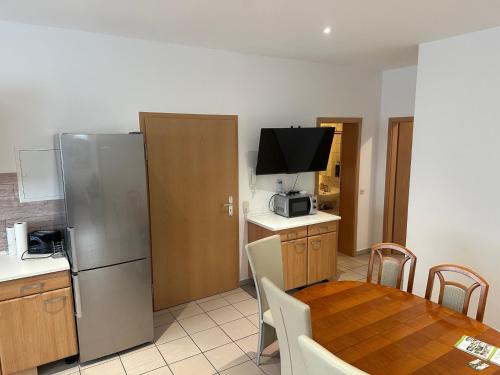 eine Küche und ein Esszimmer mit einem Tisch und einem Kühlschrank in der Unterkunft 3 Schlafzimmer, Wohnzimmer, Küche, Bad, Terrasse, Parkplatz in Wörrstadt