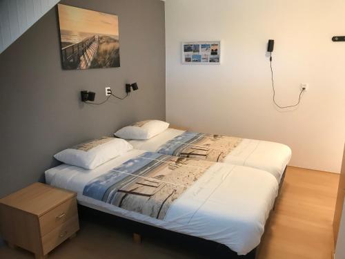 a bedroom with a large bed with white sheets at Duinoord Domburg in Domburg