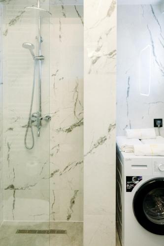 a shower and a washing machine in a bathroom at Nuance Residences - Momento in Volos