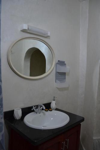 a bathroom sink with a round mirror above it at La Belle Vue Guest House in Aït Ben Haddou