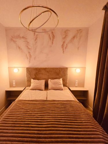 a bedroom with a large bed with a chandelier above it at Sunrise Euronia in Międzyzdroje