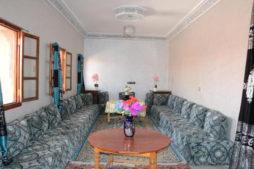 a living room with couches and a vase of flowers on a table at La Belle Vue Guest House in Aït Ben Haddou