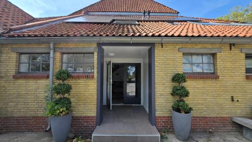 a yellow house with a door and two potted plants at Appartement Herbaijum in Herbaijum