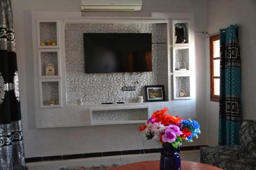 a living room with a television and a vase of flowers at La Belle Vue Guest House in Aït Ben Haddou