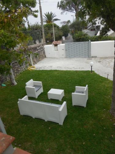a yard with three white furnitureitures on the grass at Villa Cycas in Ischia