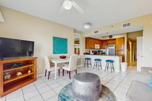a living room with a couch and a table and a kitchen at Tidewater 105 in Orange Beach