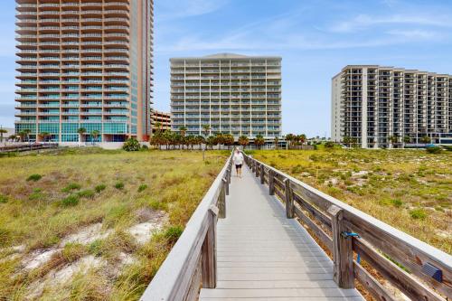 a person walking on a boardwalk over a beach with buildings at Tidewater 105 in Orange Beach