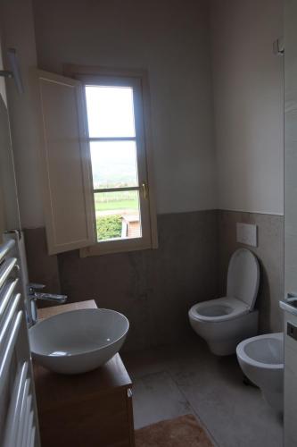 a bathroom with a toilet and a sink and a window at Podere La Saliciaia in Monsummano