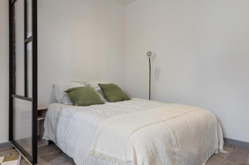 a white bedroom with a bed with green pillows at Le maquis urbain - Hostéa Oyonnax in Oyonnax
