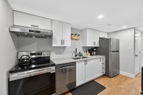 a kitchen with white cabinets and stainless steel appliances at Bright and Modern 2BR Suite with Rustic Bar in Kingston