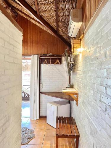 a room with a bench and a brick wall at Pousada Maxitalia in Jericoacoara