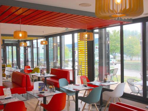 a restaurant with tables and chairs and windows at ibis Styles Lyon Sud Vienne in Chasse-sur-Rhône