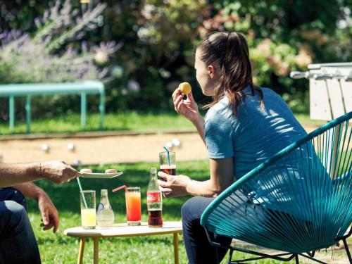 a woman sitting at a table eating a hot dog at Mercure Lyon Charbonnières in Charbonnières-les-Bains