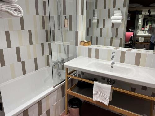 a bathroom with a sink and a tub and a mirror at Mercure Lyon Charbonnières in Charbonnières-les-Bains