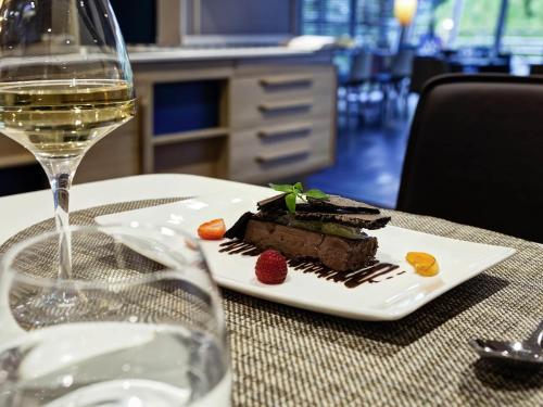 a plate of food on a table with a glass of wine at Mercure Lyon Charbonnières in Charbonnières-les-Bains