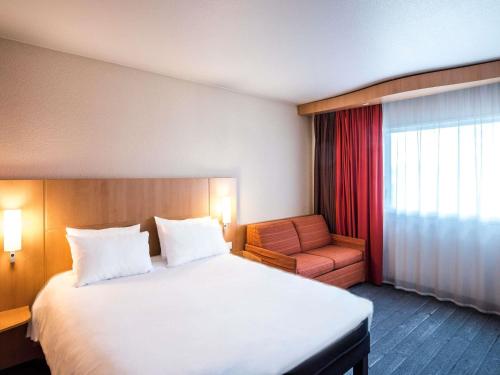 a hotel room with a large bed and a chair at ibis Metz Nord in Woippy