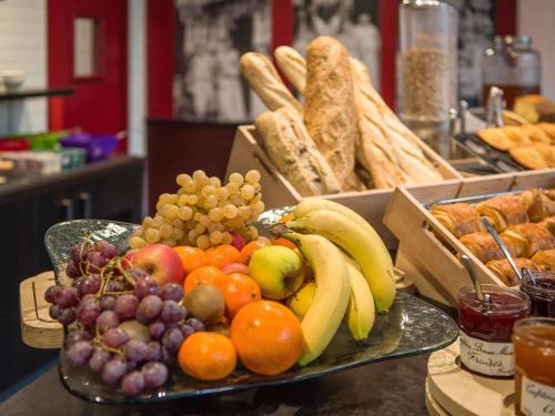 a plate of fruit and vegetables on a table with bread at ibis Metz Nord in Woippy