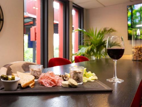 a plate of food and a glass of wine on a table at ibis Metz Nord in Woippy