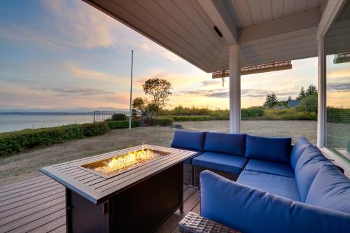 a patio with a blue couch and a fire pit at Serene Island Retreat with Beach Access and Mtn Views! in Freeland
