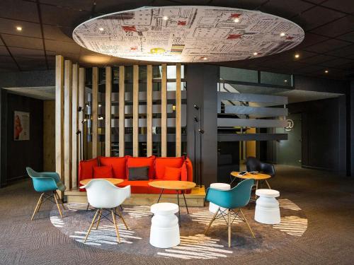 a living room with an orange couch and chairs at ibis Bordeaux Lac in Bordeaux