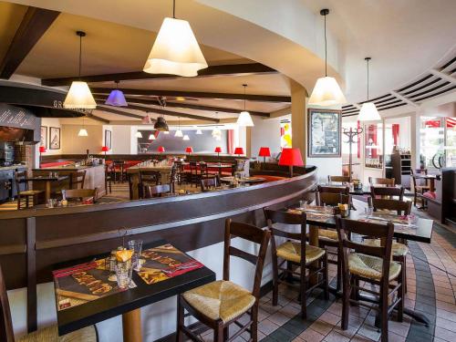 a restaurant with tables and chairs and a bar at ibis Bordeaux Lac in Bordeaux