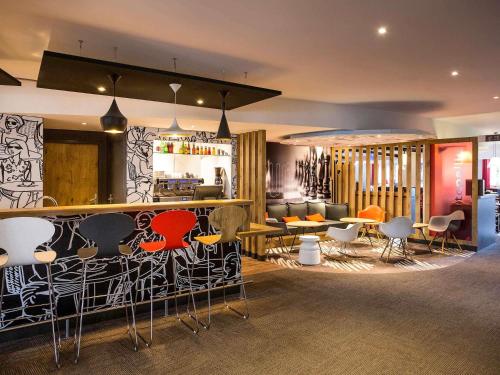 a lobby with a bar with chairs and tables at ibis Bordeaux Lac in Bordeaux