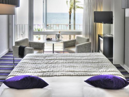 a hotel room with a large bed with purple pillows at Mercure Nice Promenade Des Anglais in Nice
