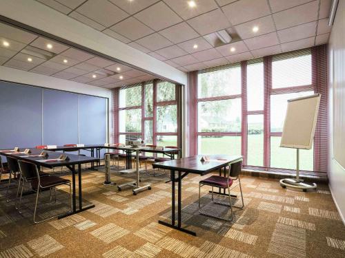 a conference room with tables and chairs and windows at ibis Charleville Mézières in Villers-Semeuse