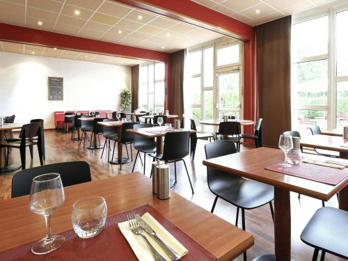 a restaurant with wooden tables and chairs and windows at ibis Charleville Mézières in Villers-Semeuse