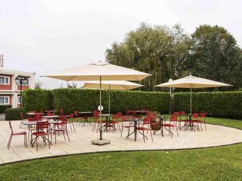 a patio with tables and chairs and umbrellas at ibis Charleville Mézières in Villers-Semeuse