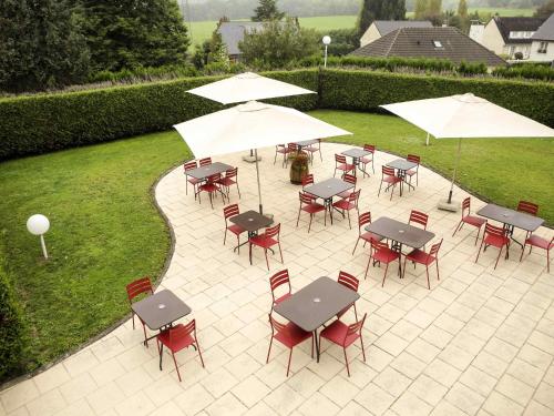 an outdoor patio with tables and chairs and umbrellas at ibis Charleville Mézières in Villers-Semeuse