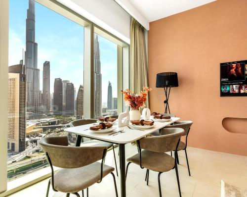 a dining room with a table and chairs and a large window at Stunning Two-Bedroom Apartment with Skyline View & walk to Dubai Mall by TerraHome in Dubai