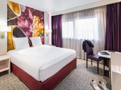 a hotel room with a bed and a desk at Mercure Strasbourg Aéroport in Ostwald
