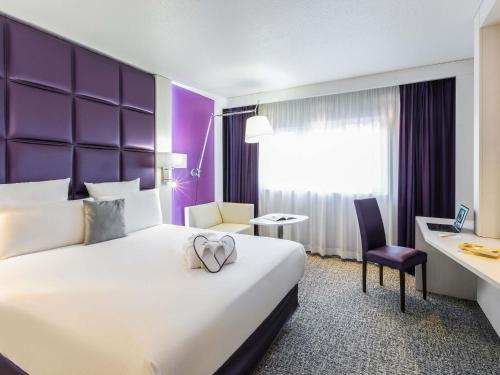 a hotel room with a large bed and a desk at Mercure Strasbourg Aéroport in Ostwald