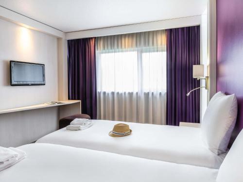 a hotel room with two beds and a window at Mercure Strasbourg Aéroport in Ostwald