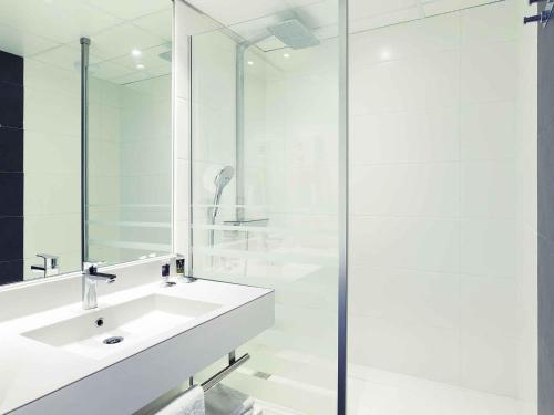 a white bathroom with a sink and a shower at Mercure Strasbourg Aéroport in Ostwald