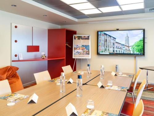 a conference room with a table and a projection screen at Mercure Toulouse Centre Saint-Georges in Toulouse