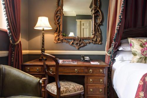 a bedroom with a bed and a desk with a mirror at The Gore London - Starhotels Collezione in London