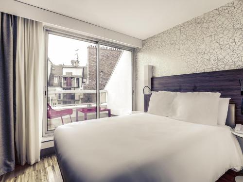 a bedroom with a large white bed and a window at Mercure Paris Arc de Triomphe Etoile in Paris