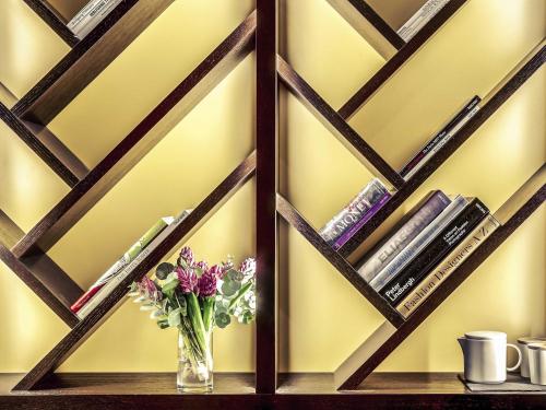 a vase of flowers on a shelf with books at Mercure Paris Arc de Triomphe Etoile in Paris