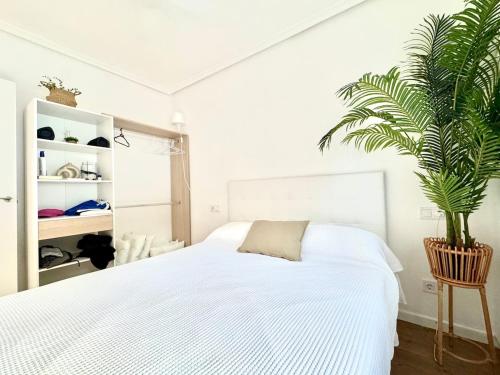 a bedroom with a white bed and a plant at Casa Rural Madrid Pantano San Juan con Piscina y BBQ in Navahondilla