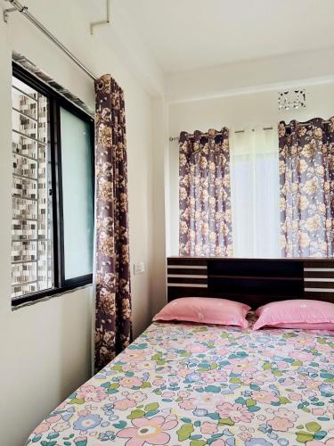 a bedroom with a bed with pink pillows and a window at Backpackers Bunkhouse Siliguri in Siliguri