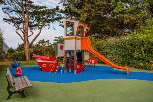 a playground with a slide and a bench on a blue carpet at Résidence Pierre & Vacances Premium Le Domaine de Cramphore in Le Pouliguen