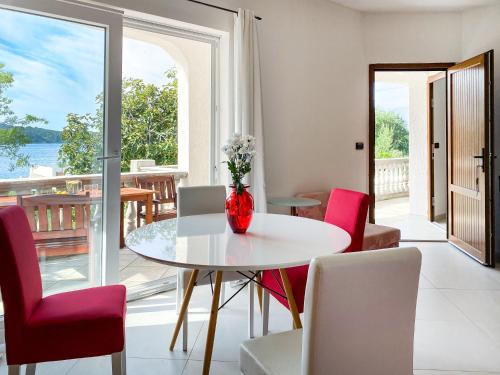 a dining room with a table and red chairs at Villa Delfin Rab in Supetarska Draga